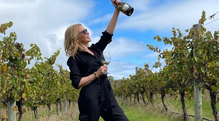 A cantora Kylie Minogue segura um vinho Chardonnay de sua marca enquanto visita vinhedos na Austrália
